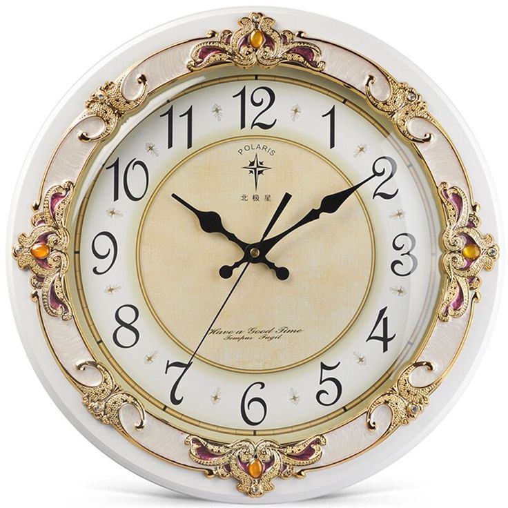 a white clock with gold trimmings and numbers on the face is shown in front of a white background