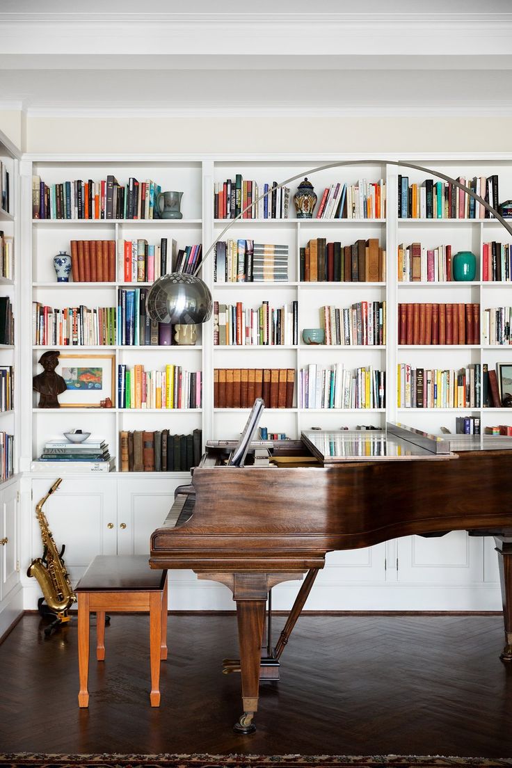 a grand piano sitting in front of a bookshelf