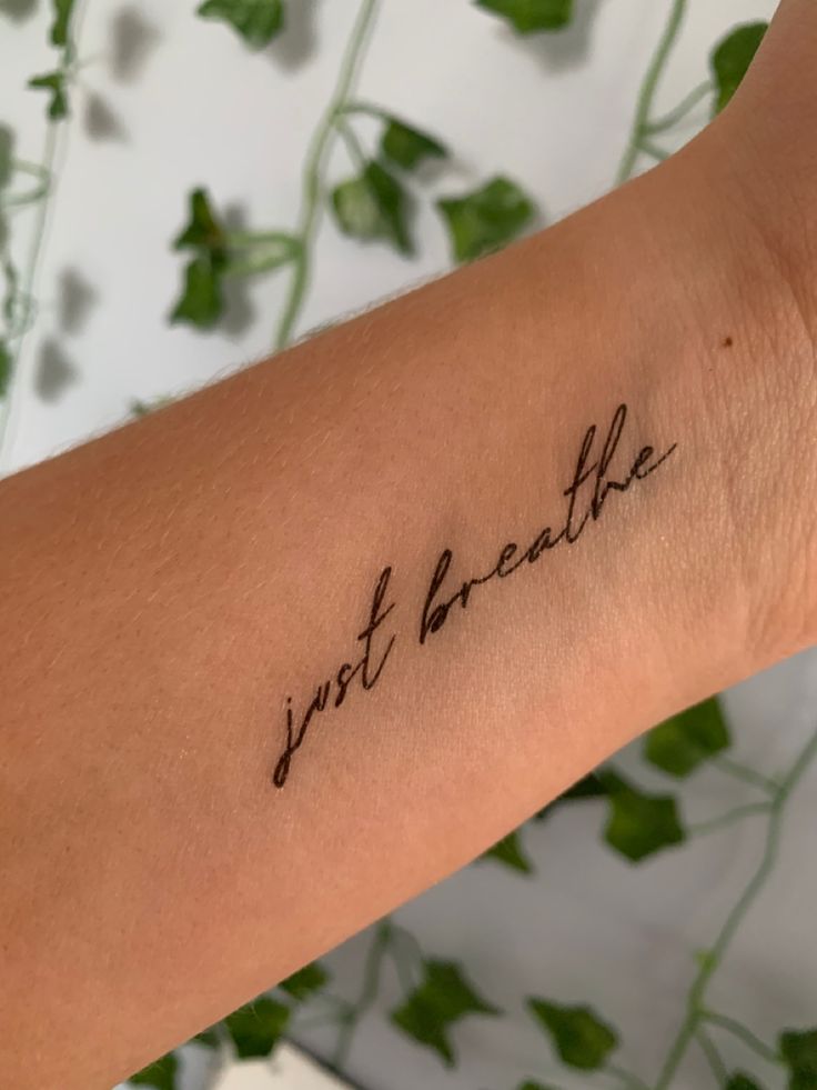 a woman's arm with the words just breathe written on it in cursive font