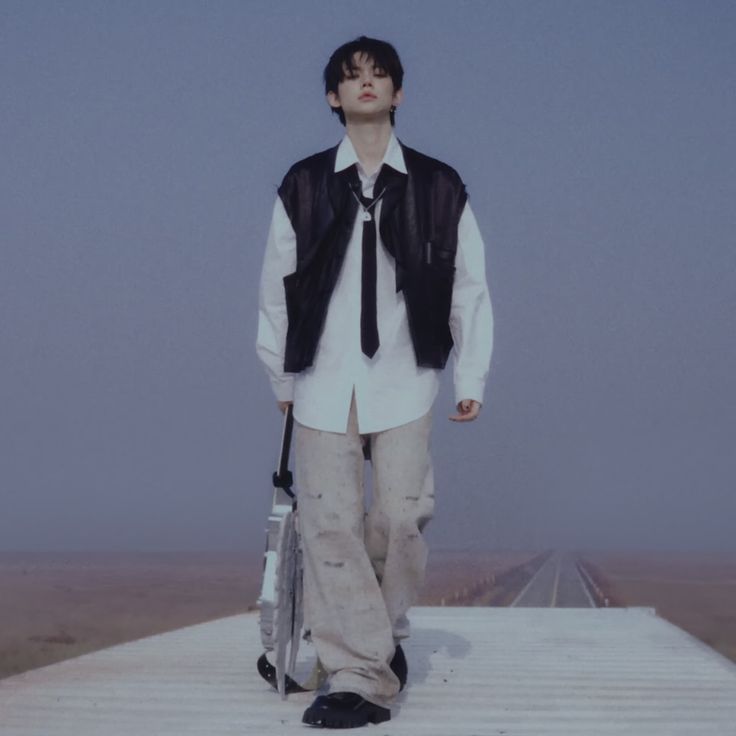 a man with a tie and vest holding an umbrella standing on a platform in the middle of nowhere