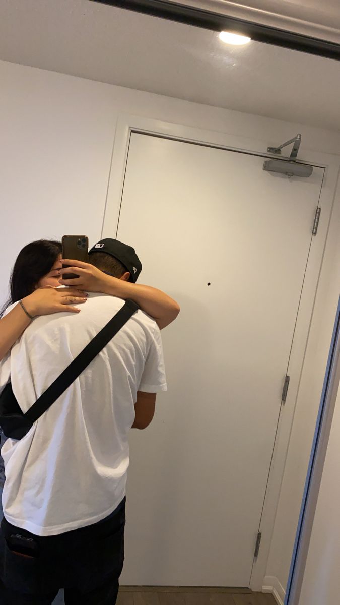 two people are hugging each other in front of a mirror