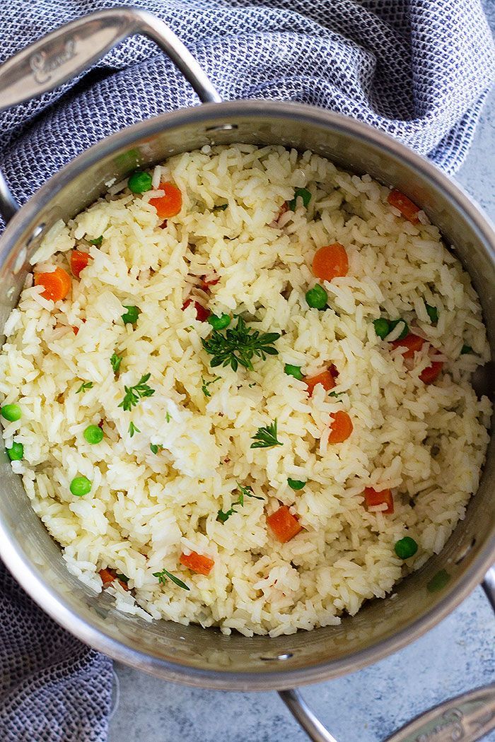 rice with carrots and peas in a pan on a blue towel next to utensils