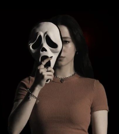 a woman holding a white mask up to her face