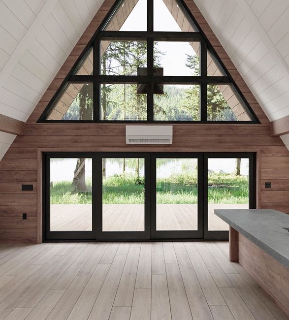 a large open room with wooden floors and vaulted ceiling, windows to the water's edge