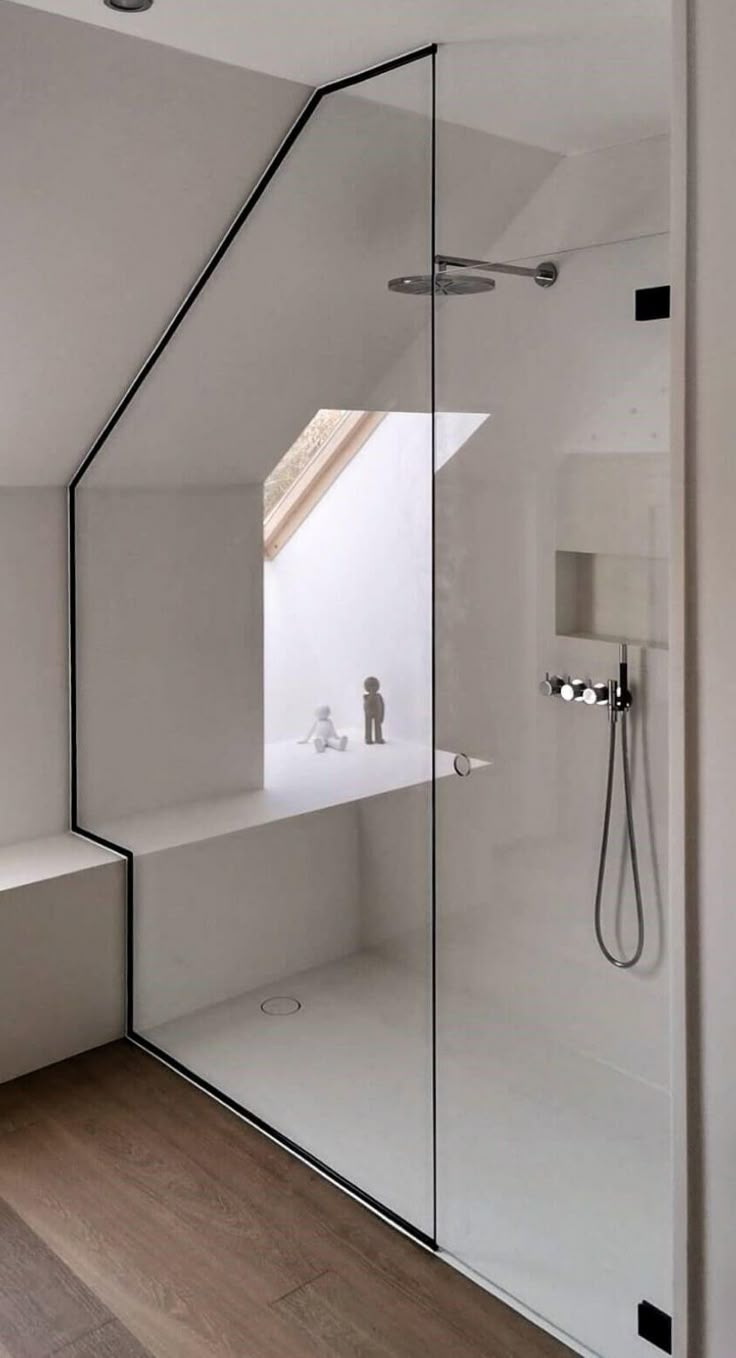 an attic bathroom with glass walls and wooden floors