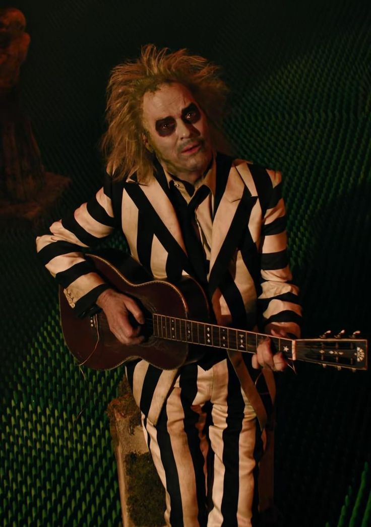 a man in striped suit playing an acoustic guitar