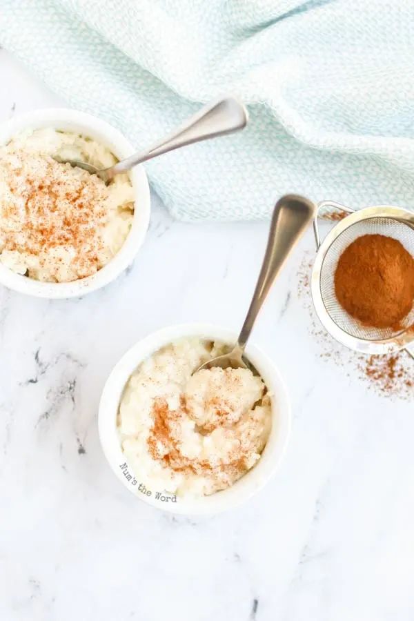 three small white bowls filled with food on top of a counter next to two spoons