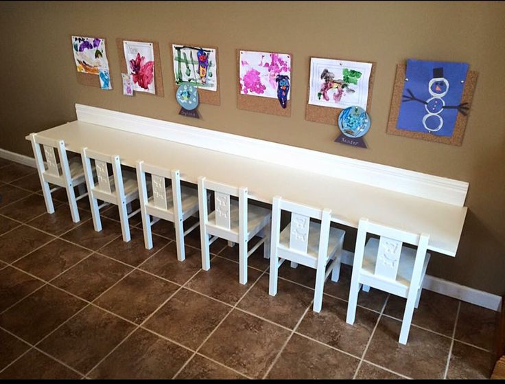 a long white bench sitting in the middle of a living room next to a wall with pictures on it