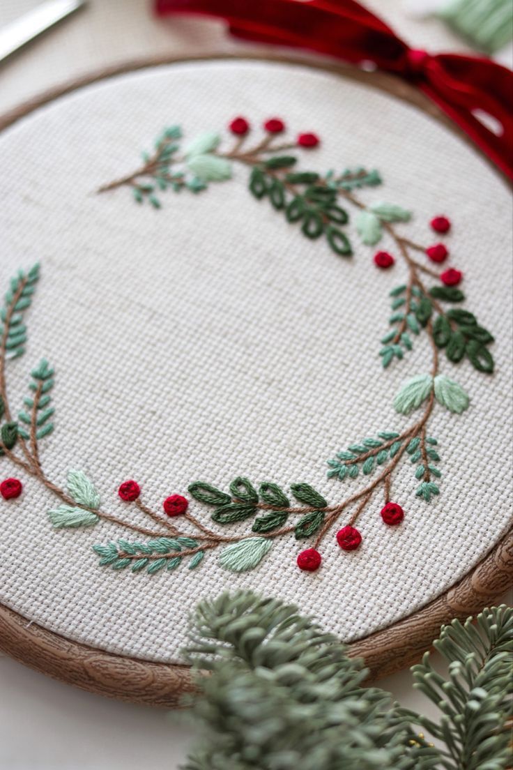 a close up of a embroidery on a piece of cloth with holly and red berries