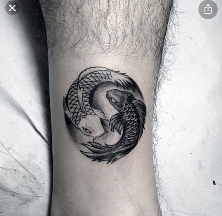 a black and white photo of a fish in a circle tattoo on the ankle area