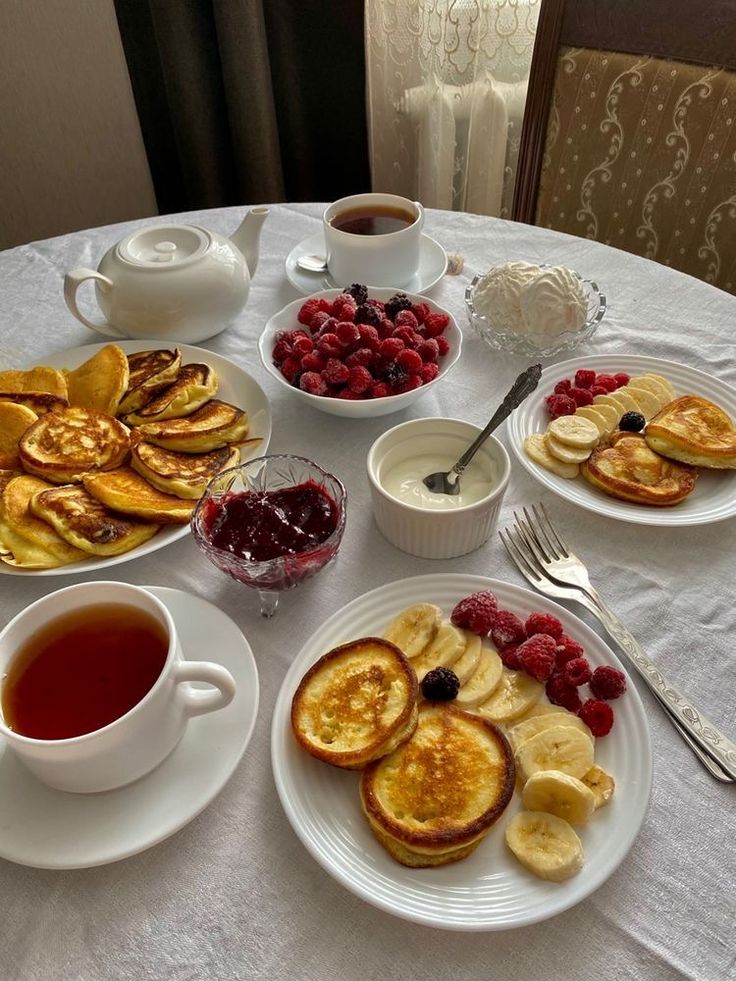 a table topped with plates of pancakes and fruit