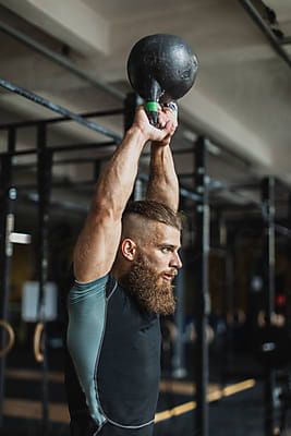 a man is lifting a medicine ball up in the air with one hand and another on his head