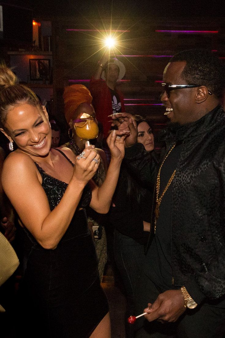 a man and woman standing next to each other at a party with one holding an object in his hand