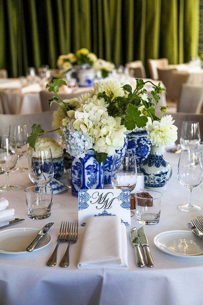 the table is set with blue and white dishes, silverware, and napkins