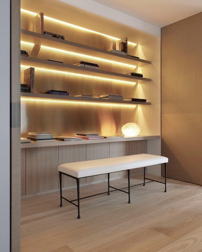 a white bench sitting in front of a shelf filled with books