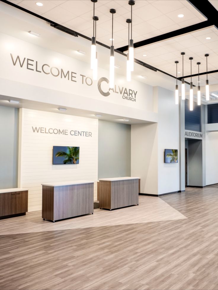 an empty lobby with wooden flooring and lights hanging from the ceiling above it is a welcome sign that reads, welcome to clavery center