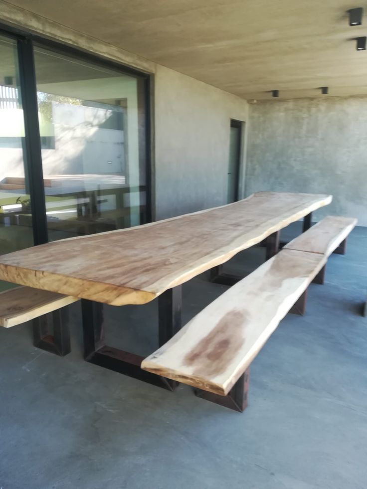 a wooden bench sitting in front of a glass window on top of a cement floor