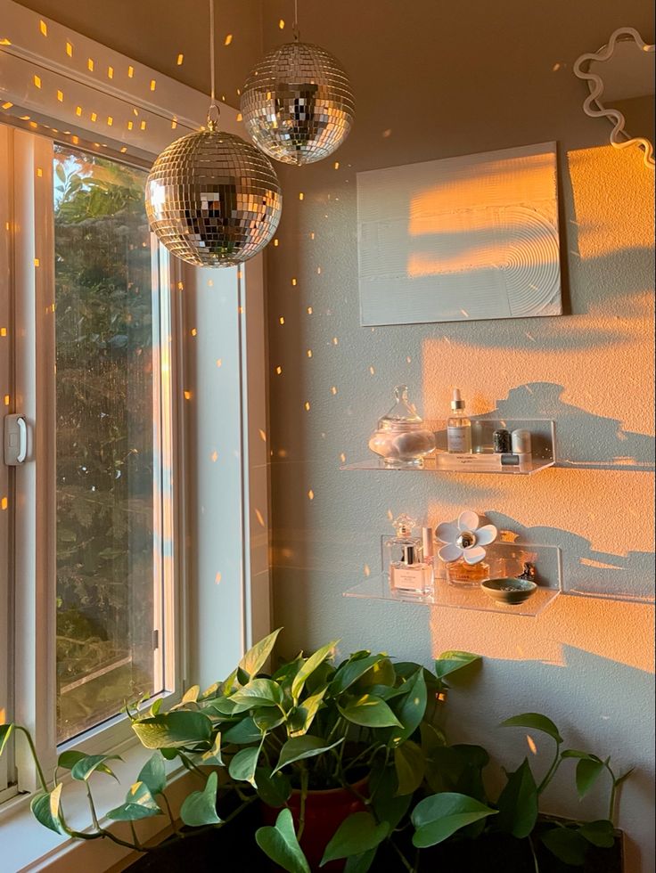 two disco ball lights hanging from the ceiling above a potted plant in front of a window