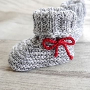 a pair of crocheted baby booties with a red bow on the side