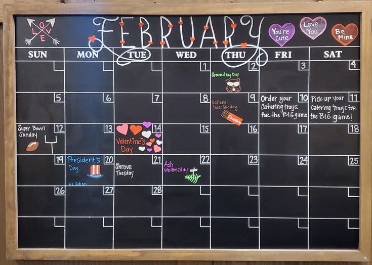 a chalk board with calendars written on it and hearts drawn on the wall next to it