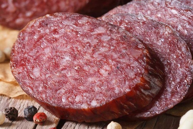 two pieces of sausage sitting on top of a wooden table