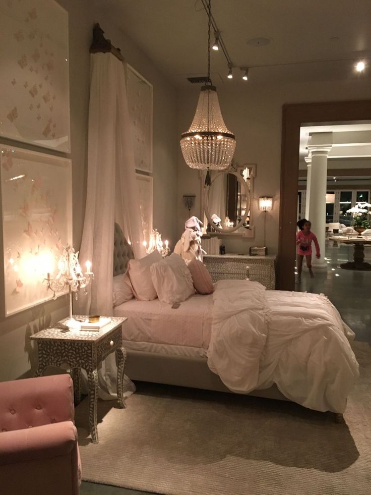 a bed room with a neatly made bed next to two chairs and a chandelier