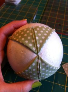 a person holding a ball on top of a cutting mat next to scissors and tape