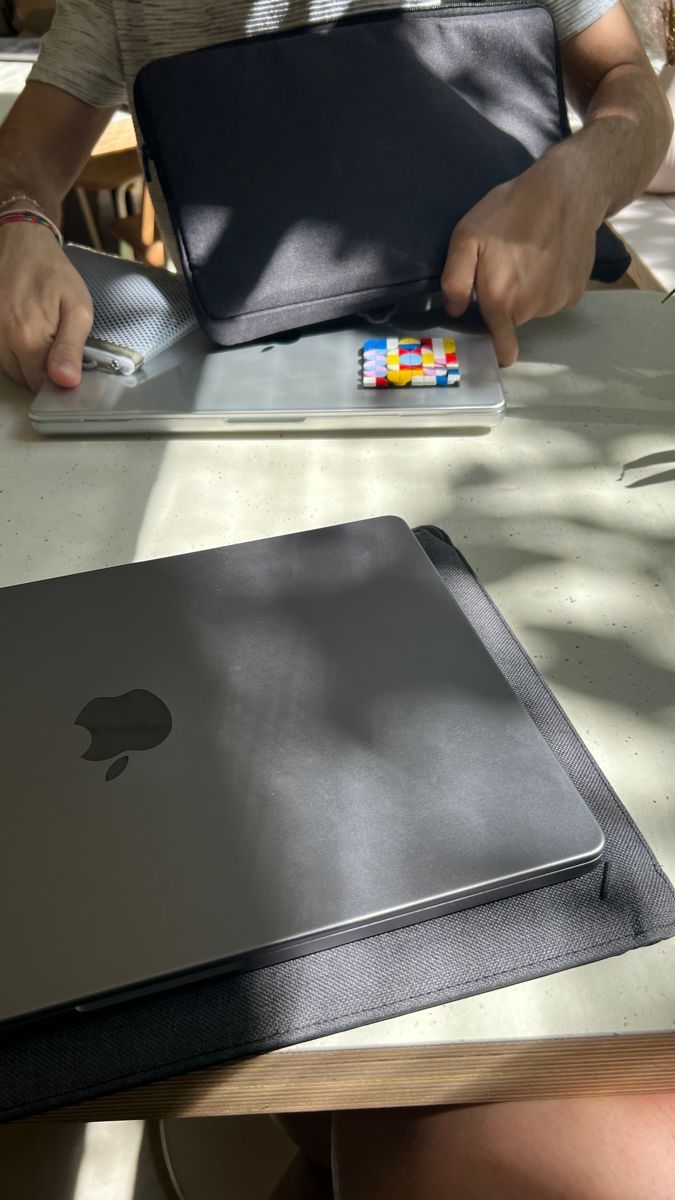 a person sitting at a table with an apple laptop