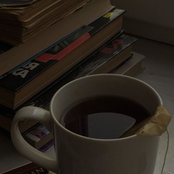 a cup of coffee sitting on top of a pile of books