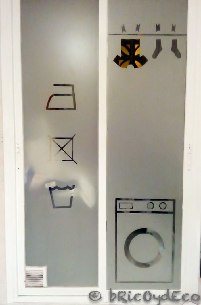 a washer and dryer are on display in a room with glass doors that have symbols drawn on them