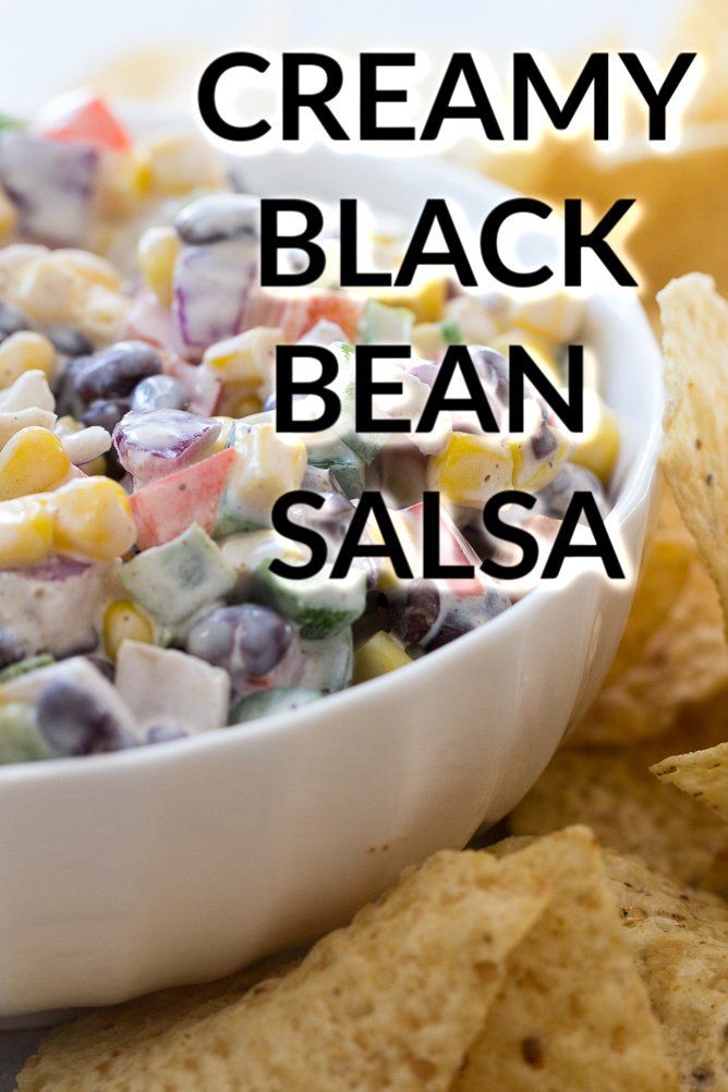 a white bowl filled with black bean salsa next to corn and tortilla chips