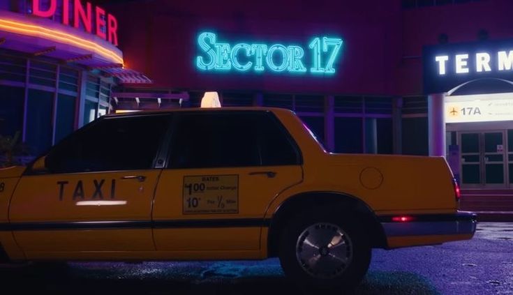 a taxi cab parked in front of a building with neon signs on it's sides