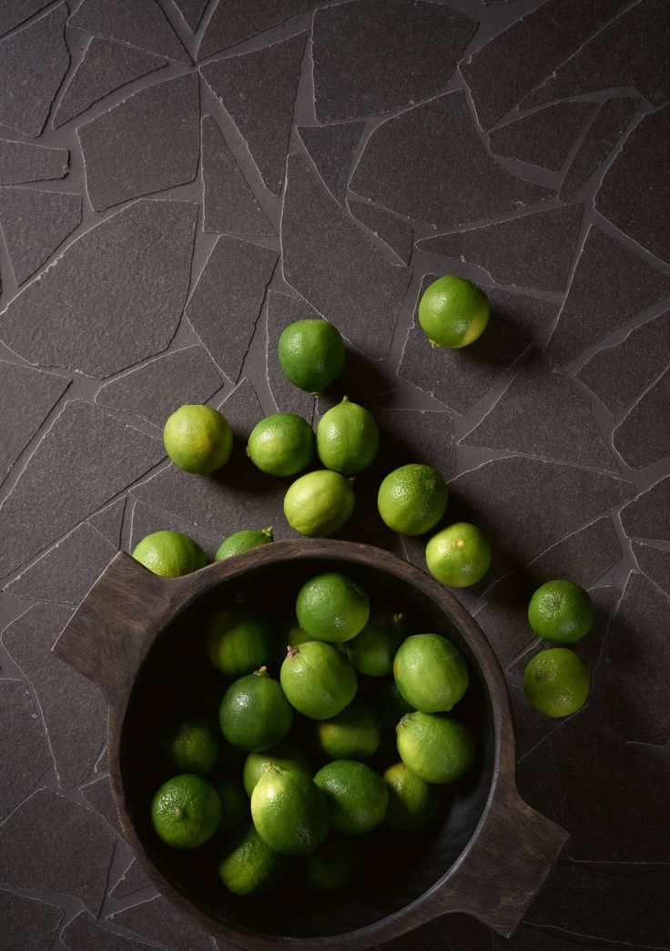 limes are sitting in a bowl on the floor