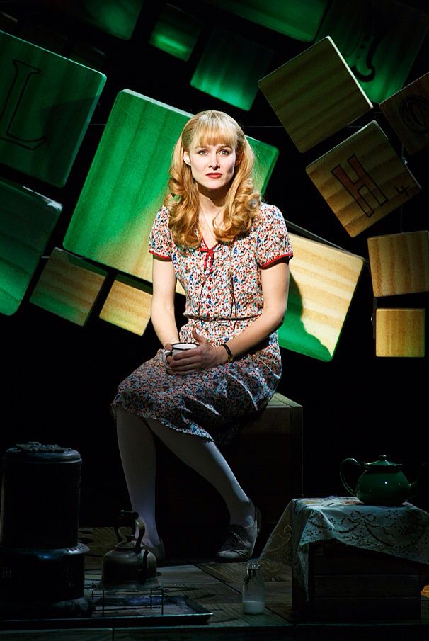 a woman sitting on top of a wooden bench in front of green light cubes