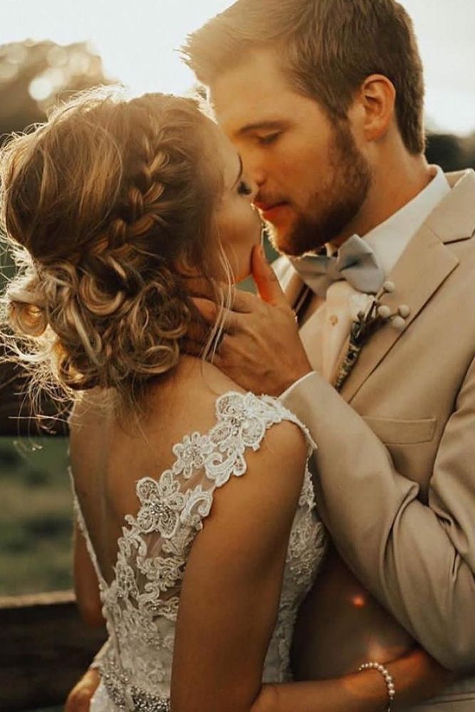 a bride and groom kissing in the middle of a path with greenery on either side