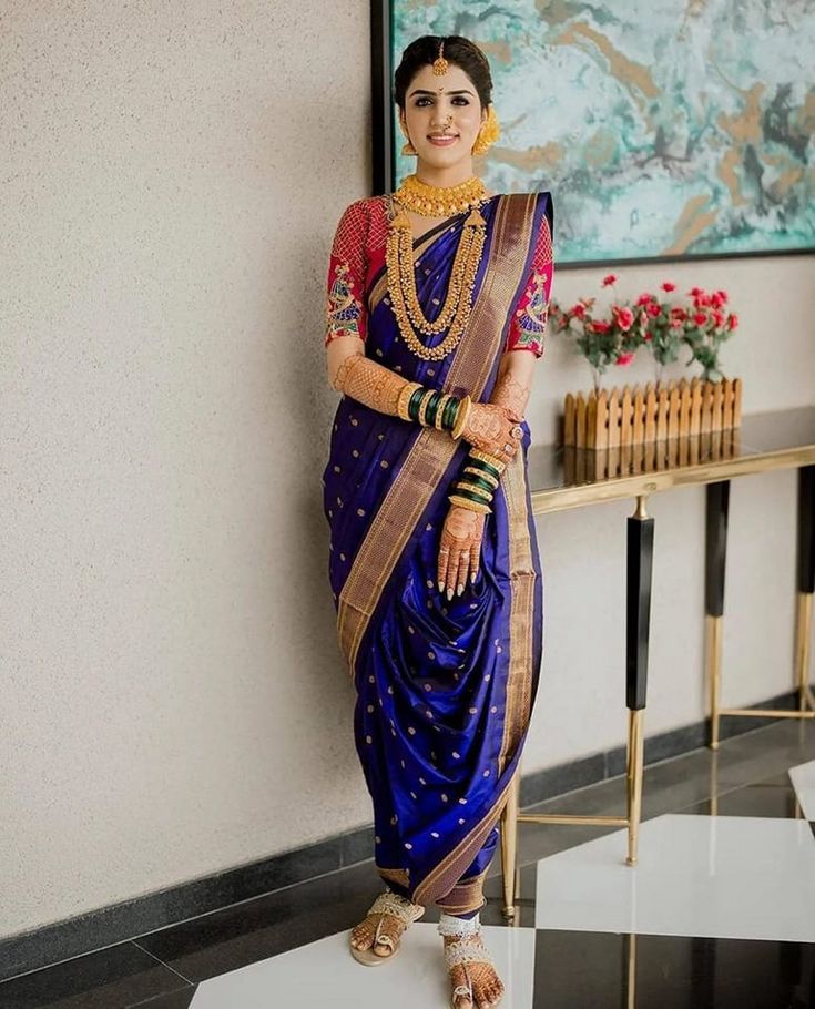 a woman in a blue and gold sari standing next to a painting on the wall