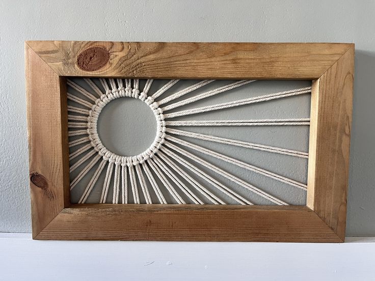 a wooden frame with string art in the shape of a sunburst on it