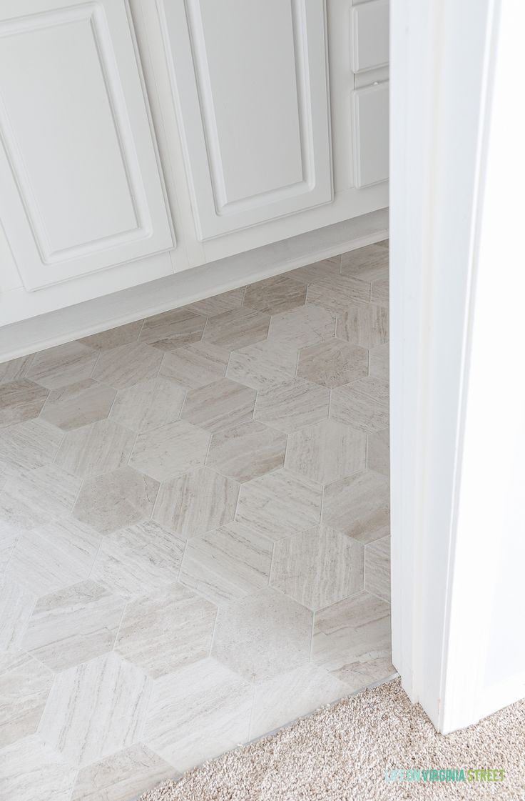 a kitchen with white cabinets and flooring next to a door way that leads to another room