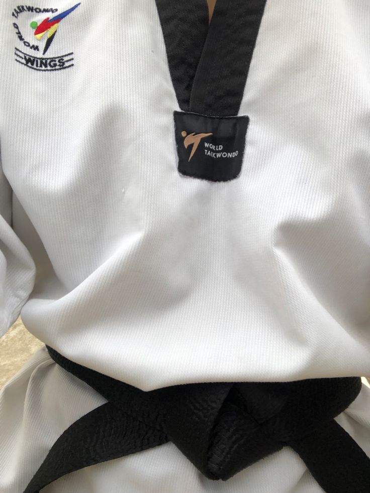 the back view of a person wearing a white karate uniform with black belt and gold medal