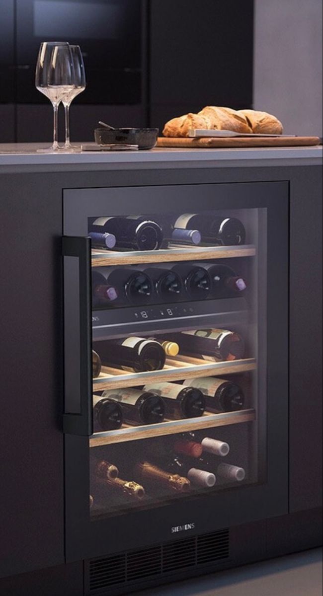 a wine cooler with several bottles and glasses on the counter