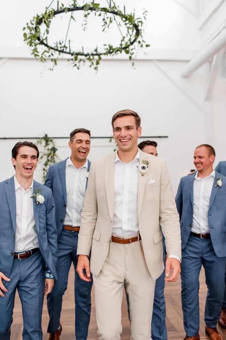 a group of men standing next to each other wearing suits and smiling at the camera