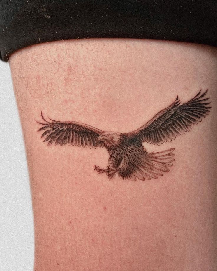 an eagle tattoo on the side of a woman's thigh