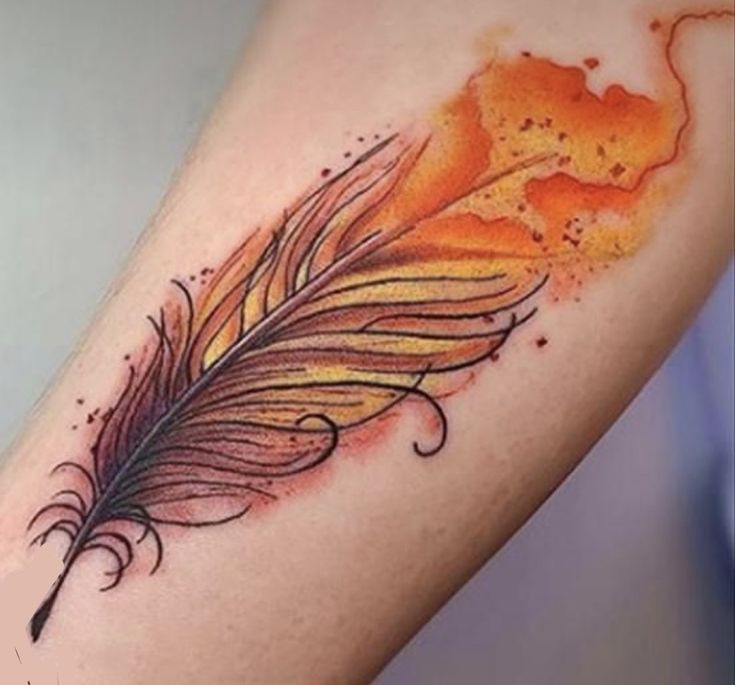 an orange and black feather tattoo on the left arm with watercolor splashes around it