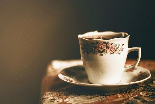 a tea cup and saucer sitting on top of a wooden table next to a wall