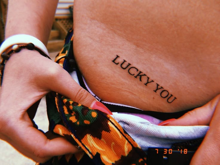 a close up of a person's stomach with the words lucky you tattooed on it