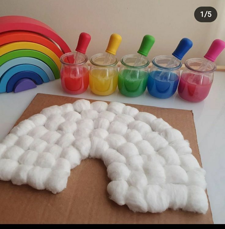 a cardboard box filled with white foam next to rainbows and paint bottles on top of a table