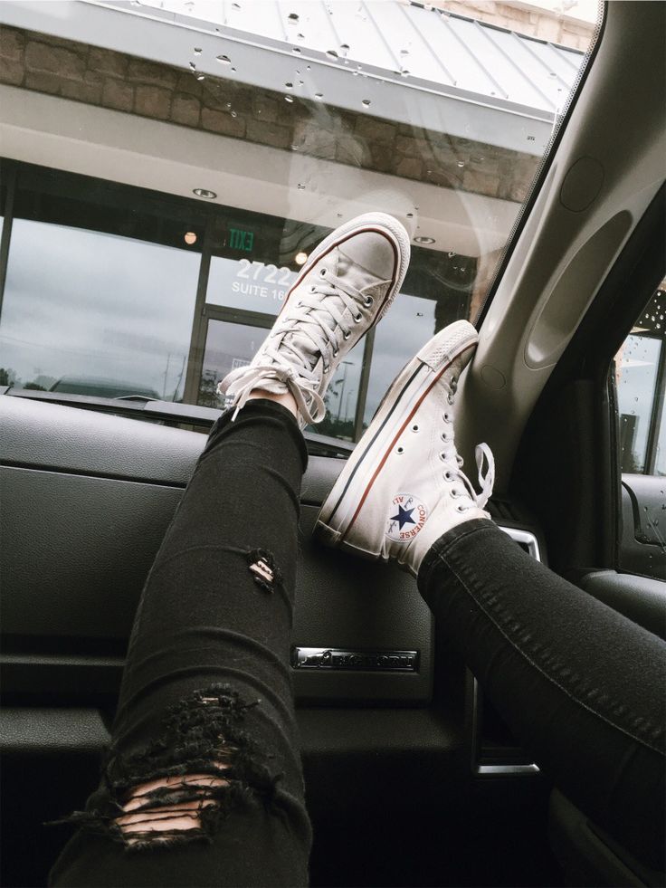 a person sitting in the passenger seat of a car with their feet on the dashboard