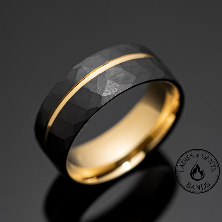 a black and gold wedding ring with a diamond in the center on a dark background