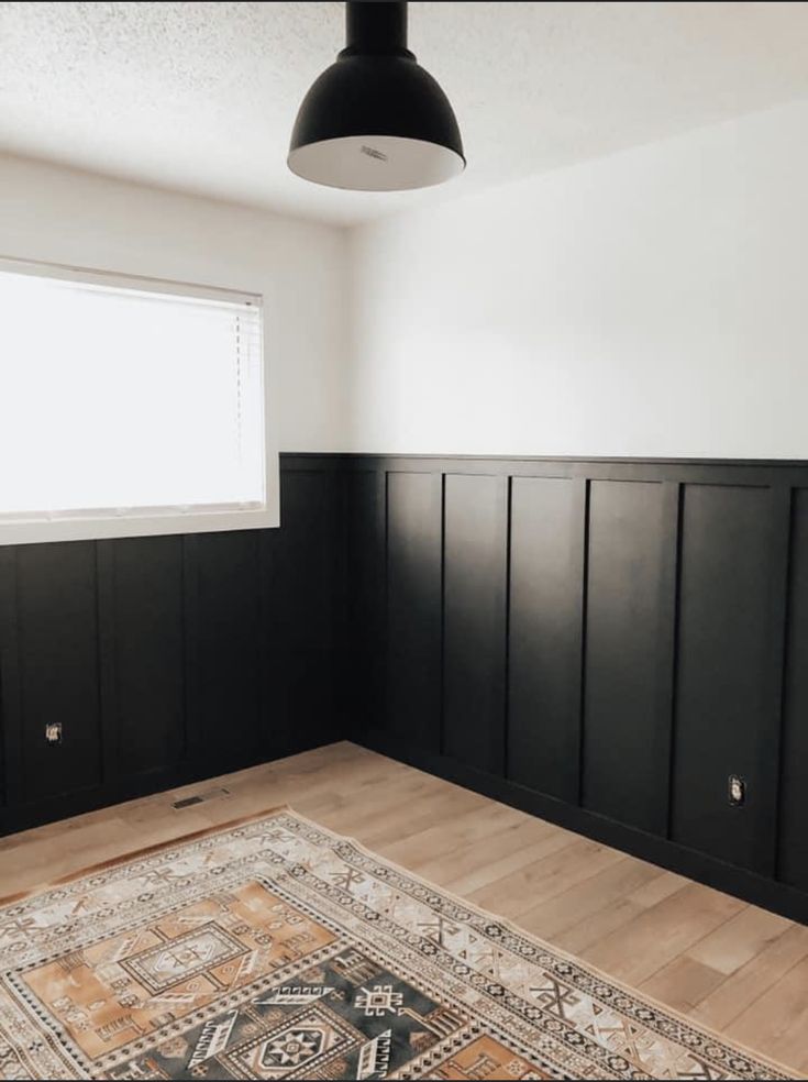 an empty room with black paneling and wooden floors