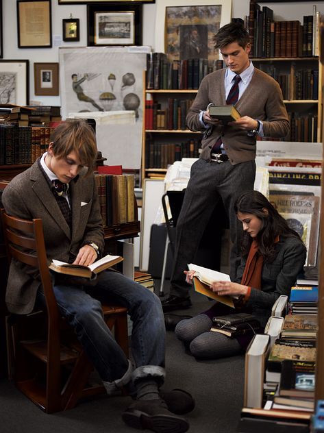 three people sitting in chairs reading books and looking at something on the floor next to them